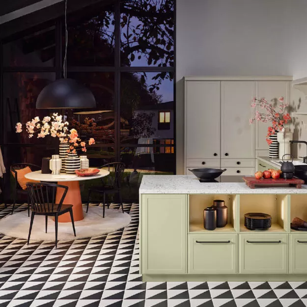 Nolte Küche Torino Lack in Avocado und Kaschmir Softmatt mit Kücheninsel, offenen Regalen und Essbereich – moderne Landhausküche von Willemsen Küchen.